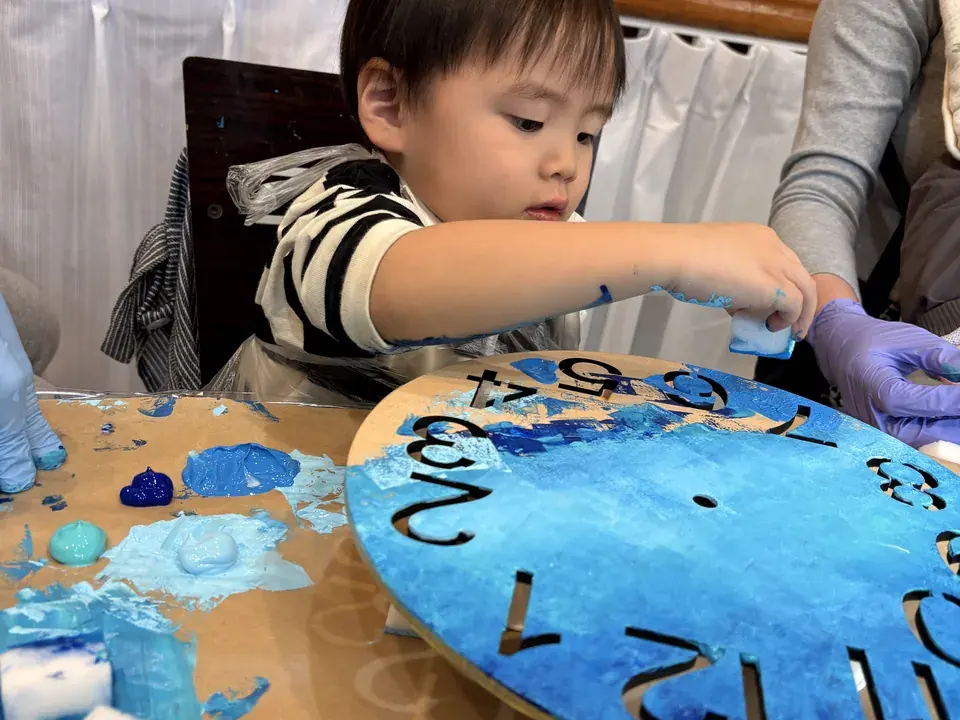 青いレジンを時計の文字盤にのせる小さな男の子